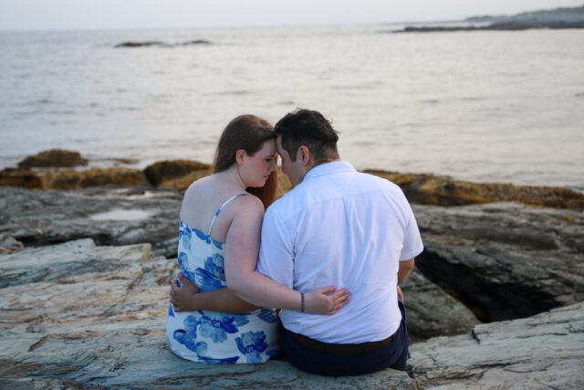 Couple sitting together by the ocean.