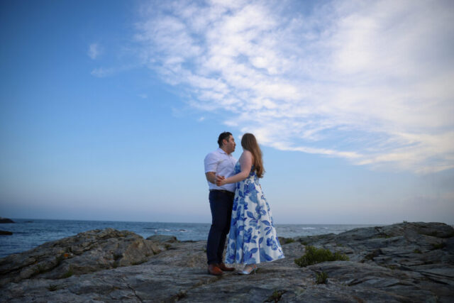 Couple embracing on rocky shoreline.